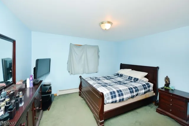 a bedroom with a bed and a flat tv screen on dresser
