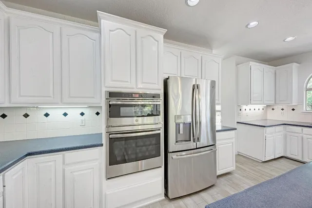 a kitchen with granite countertop white cabinets and stainless steel appliances