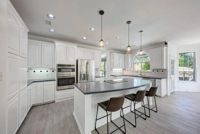 a kitchen with stainless steel appliances kitchen island granite countertop a kitchen island hardwood floor and a sink