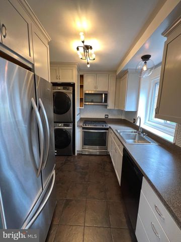 a large kitchen with a sink stainless steel appliances and a refrigerator