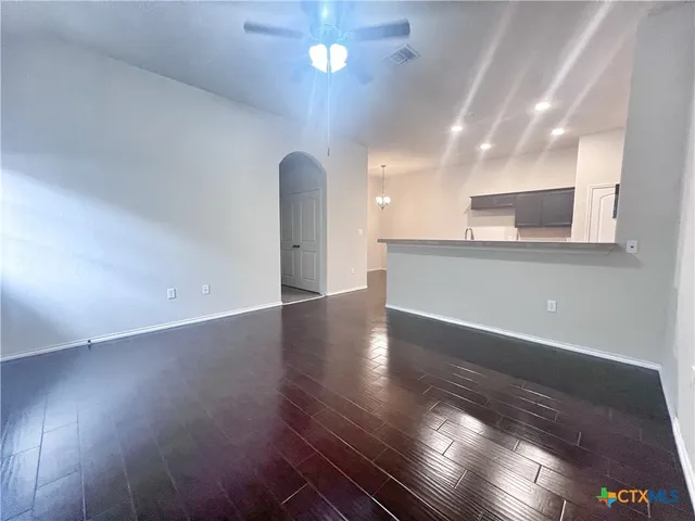 an empty room with wooden floor and kitchen view