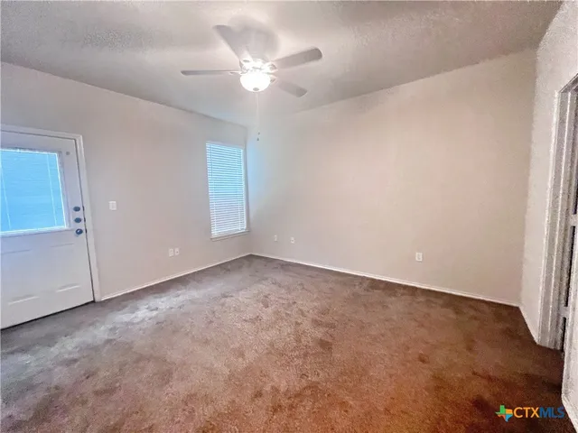 an empty room with a chandelier fan and windows