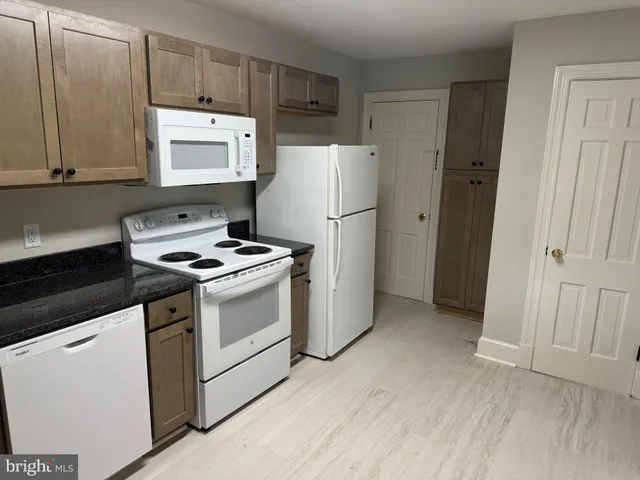 a kitchen with granite countertop white cabinets and white appliances