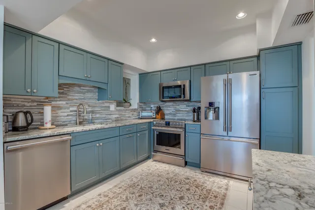 a kitchen with stainless steel appliances granite countertop a refrigerator sink and stove