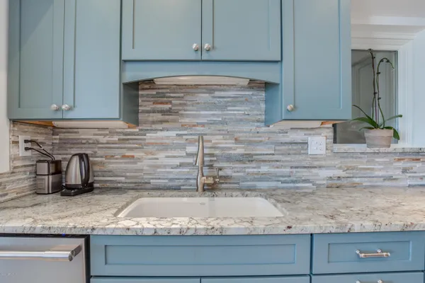 a kitchen with granite countertop a sink and white cabinets
