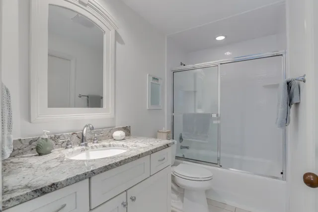 a bathroom with a granite countertop sink toilet and shower