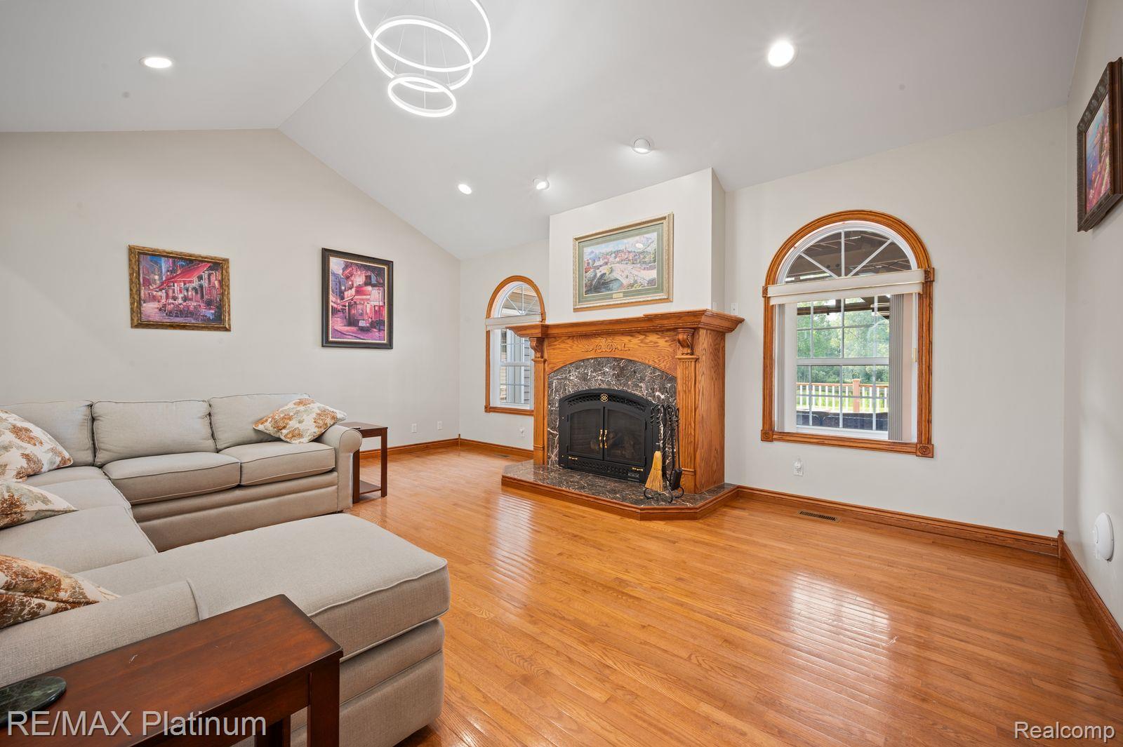 8922 McClements Road Brighton, MI 48114 - Photo 12 of 65 Spacious living area featuring a vaulted ceiling with recessed lighting, a decorative chandelier, and wood-finish flooring