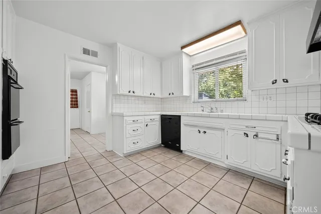 a kitchen with white cabinets appliances and a window