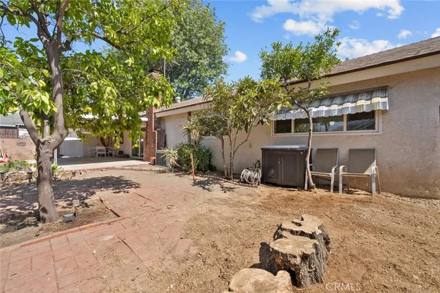 a backyard of a house with table and chairs under an umbrella