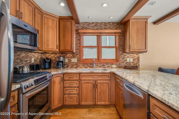 a view of a dining room with furniture a kitchen view and a chandelier
