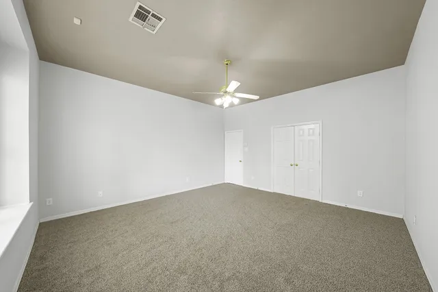 an empty room with a chandelier fan and windows