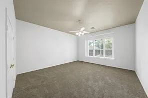 an empty room with a chandelier fan and windows