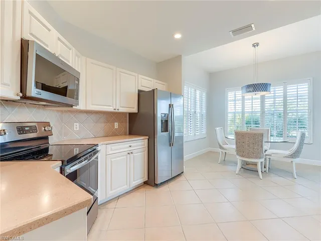 a kitchen with granite countertop a refrigerator stove and white cabinets