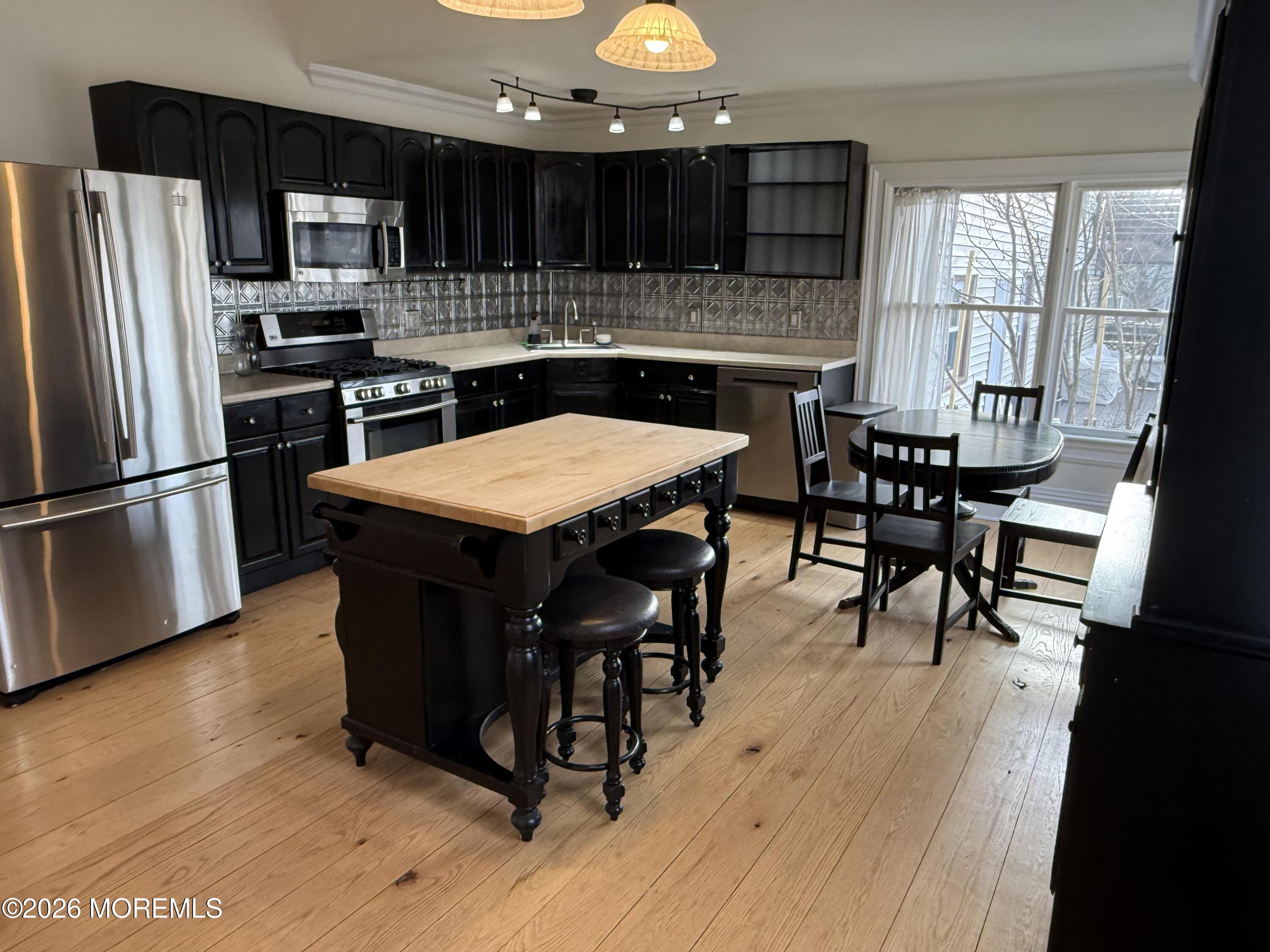 a kitchen with stainless steel appliances a dining table chairs stove and refrigerator