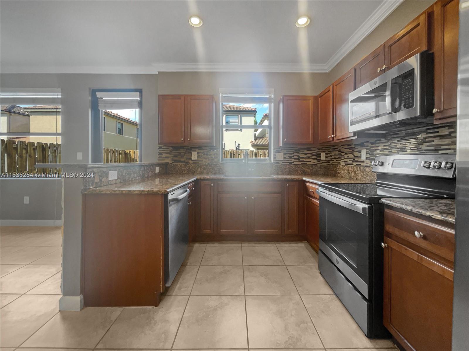 11351 Southwest 240th Street, Unit 1 Homestead, FL 33032 - Photo 8 of 24 a kitchen with stainless steel appliances granite countertop a sink counter space cabinets and a large window