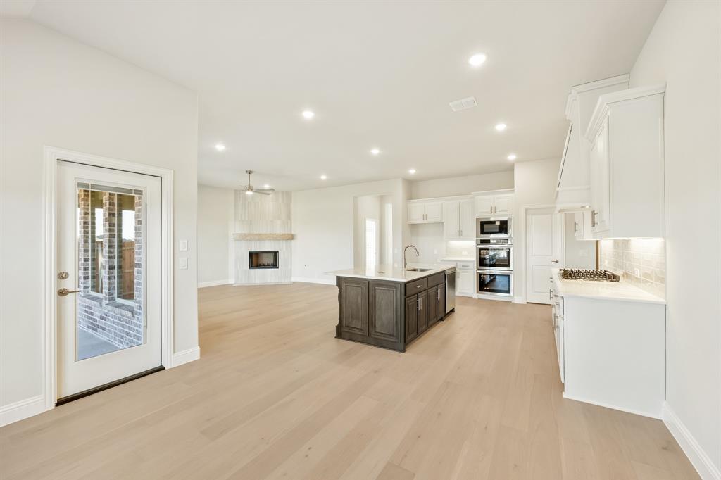 1024 Silver Sage Drive Justin, TX 76247 - Photo 18 of 35 a large white kitchen with kitchen island a stove a refrigerator a sink and white cabinets with wooden floor