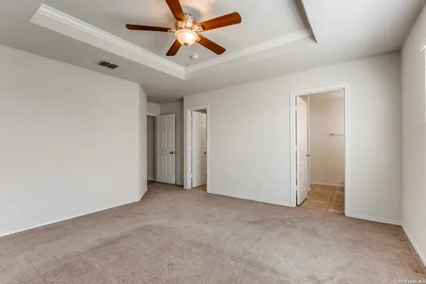 an empty room with a ceiling fan and windows