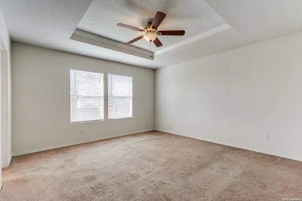 an empty room with a ceiling fan and carpet