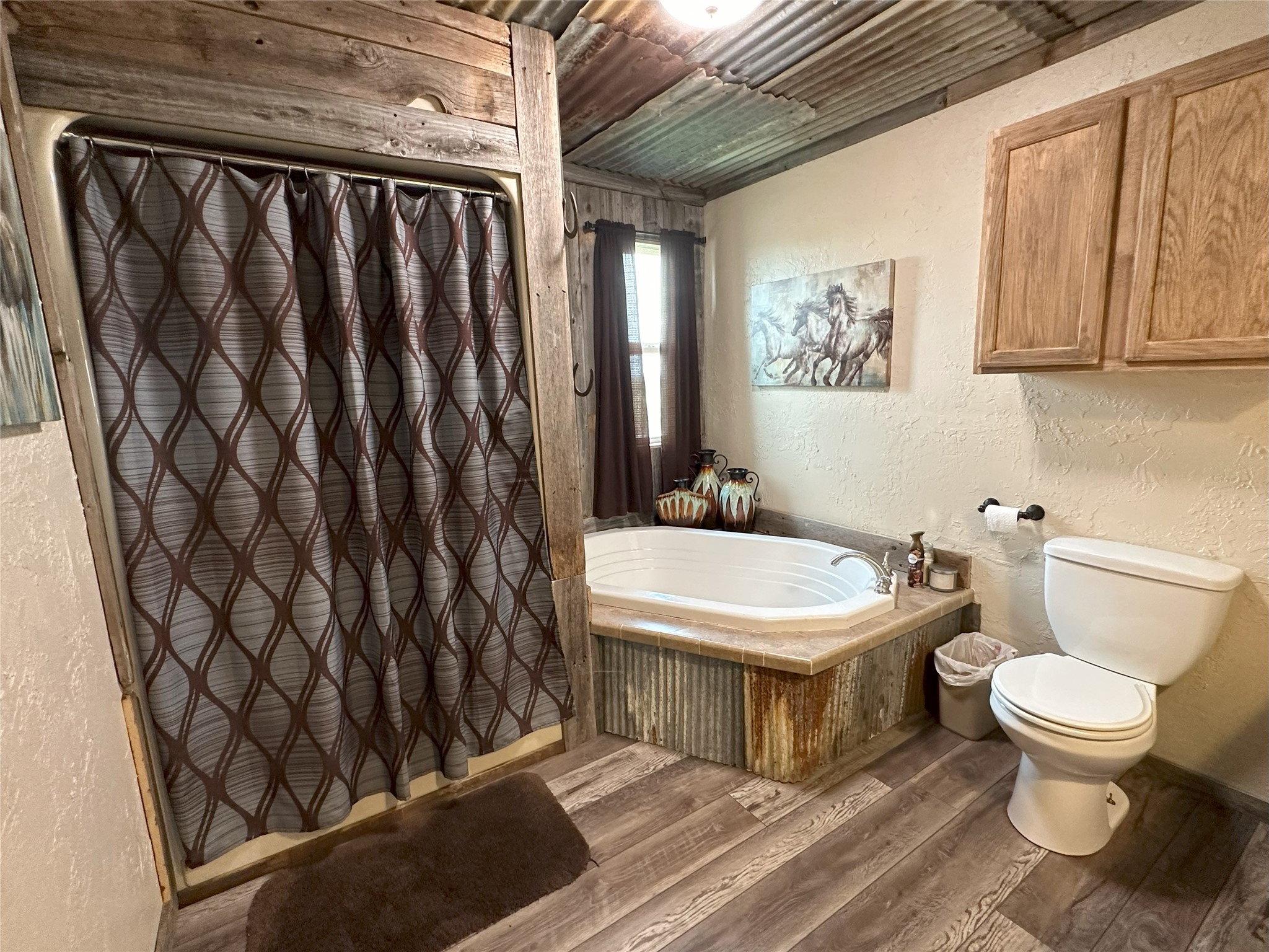 906 C R 235 Old Glory, TX 79540 - Photo 17 of 40 Full bathroom featuring wood finished floors, a garden tub, toilet, a textured wall, and a shower with shower curtain