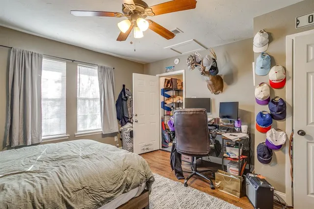 a bedroom with a bed and dresser with wooden floor