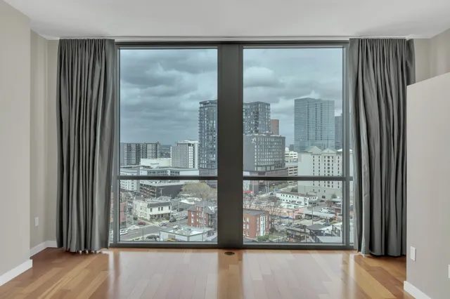 a view of a room with a large window and wooden floor