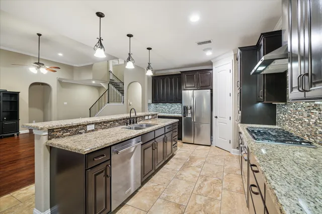 a large kitchen with kitchen island a stove a sink refrigerator and a wooden floor