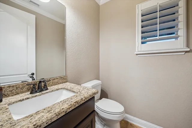 a bathroom with a granite countertop sink and a toilet