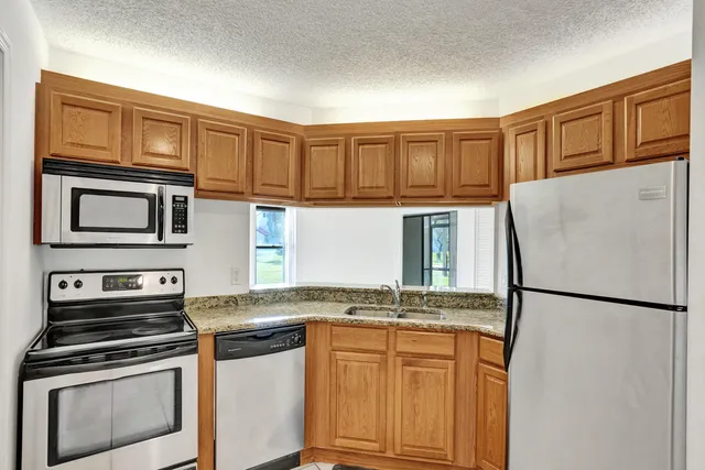 a kitchen with stainless steel appliances granite countertop a refrigerator stove top oven and sink