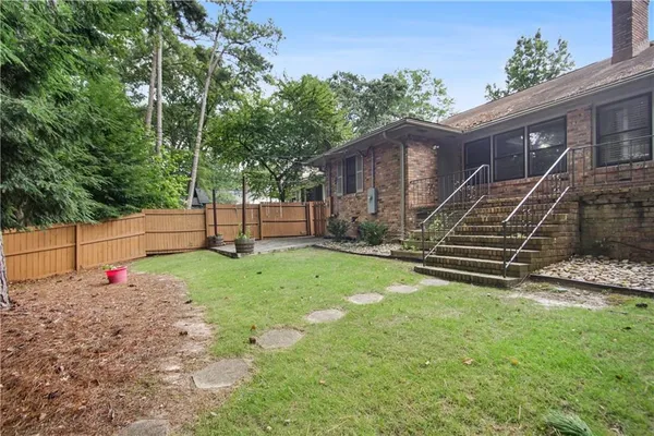 a view of backyard with wooden fence and a large tree