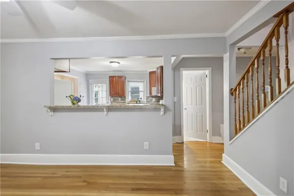 a view of a living room with wooden floor and kitchen view