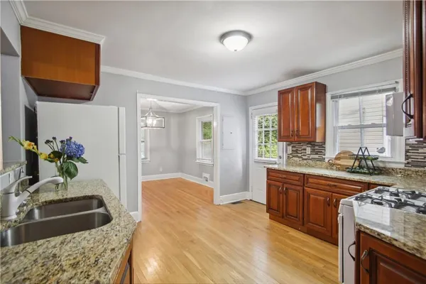 a large kitchen with granite countertop a sink stove and cabinets