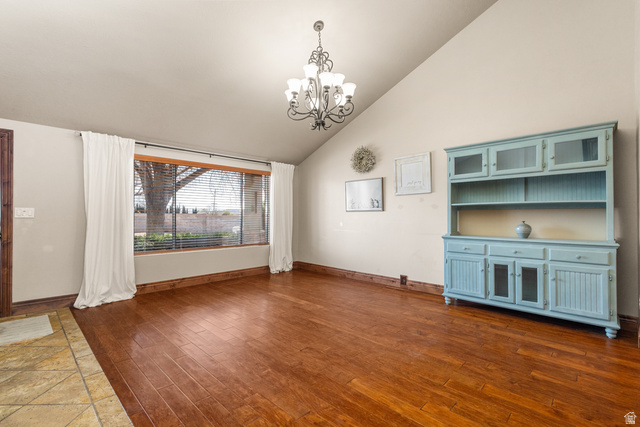 892 Cambridge Drive St. George, UT 84770 - Photo 31 of 65 Vaulted ceiling with a chandelier, wood-finish flooring, a large window with blinds, and contrasting tiled entry