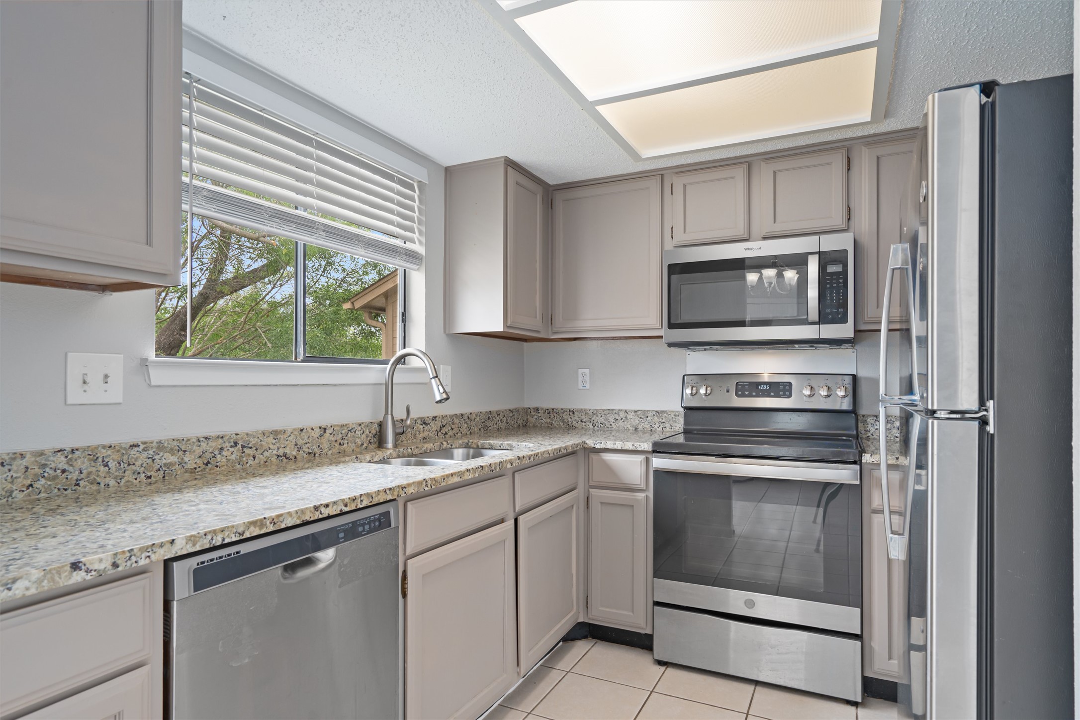 13357 Water Oak Lane, Unit A Austin, TX 78729 - Photo 6 of 26 a kitchen with stainless steel appliances granite countertop a sink stove microwave and refrigerator