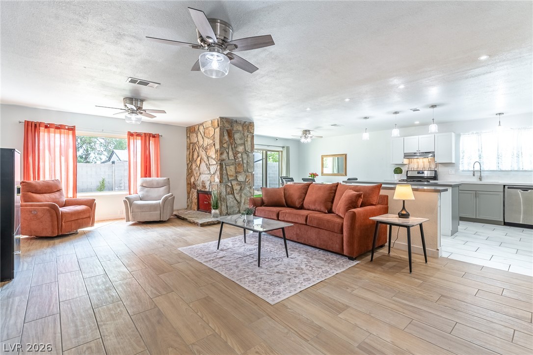 An open-concept living area boasts wood-look tile flooring and a dual-sided stone fireplace.