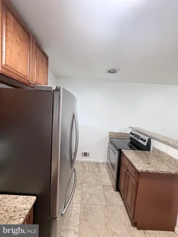 a kitchen with stainless steel appliances granite countertop a refrigerator a stove and a sink with wooden cabinets