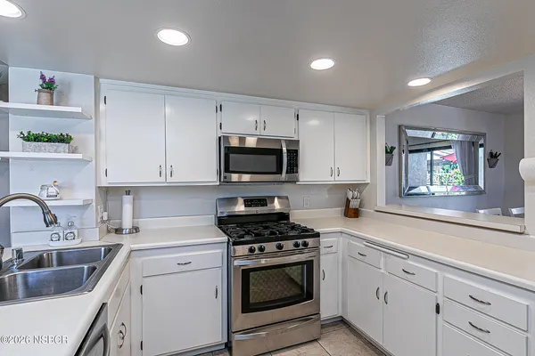 a kitchen with granite countertop white cabinets and stainless steel appliances