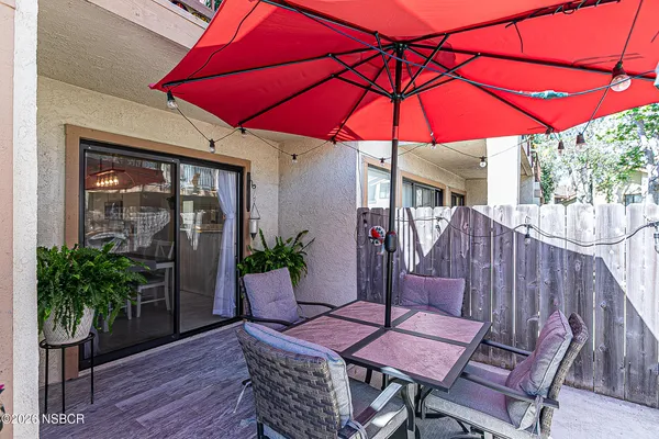 a patio with a table and chairs under an umbrella