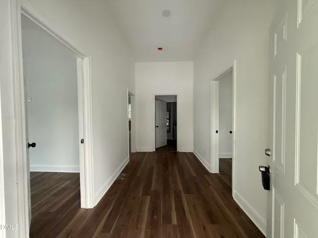 a view of a hallway with wooden floor and a bathroom
