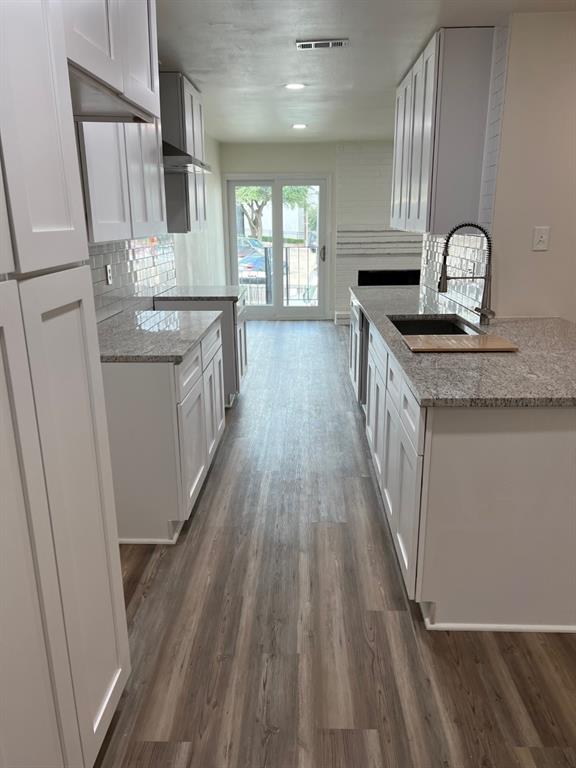 a kitchen with granite countertop a sink appliances wooden floor and cabinets