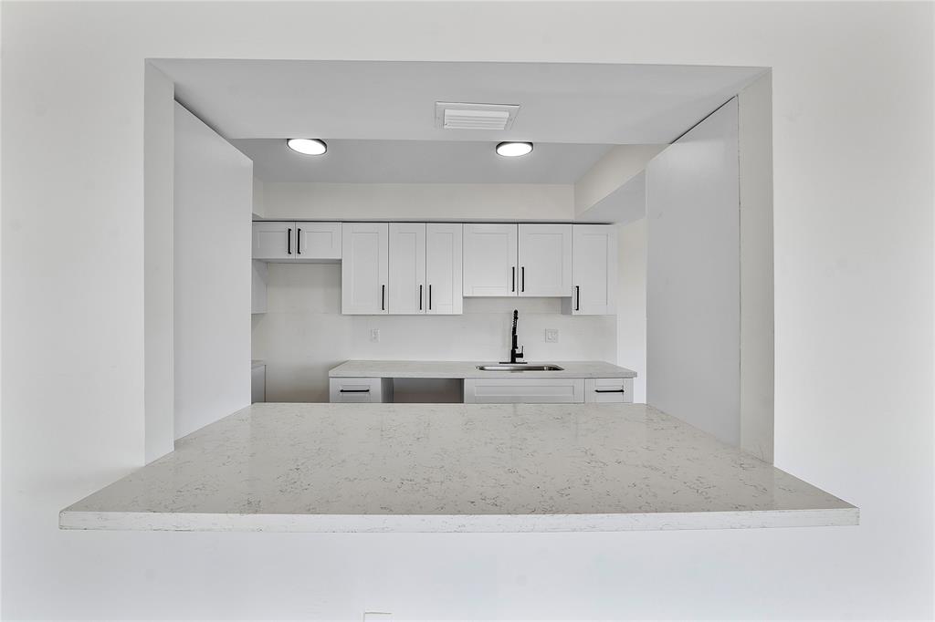 4174 Inverrary Drive, Unit 1002 Lauderhill, FL 33319 - Photo 10 of 28 a large white kitchen with kitchen island stainless steel appliances sink and cabinets