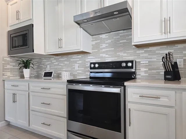 a kitchen with stainless steel appliances granite countertop white cabinets and a stove top oven