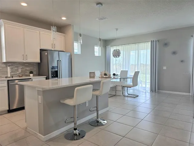 a large kitchen with kitchen island granite countertop a living room and white cabinets