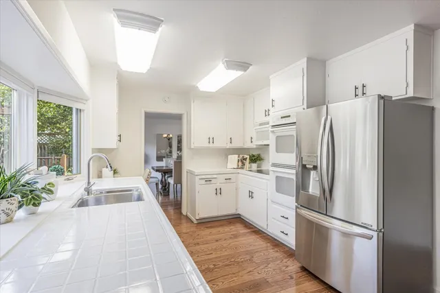 a large white kitchen with stainless steel appliances granite countertop a refrigerator and a sink