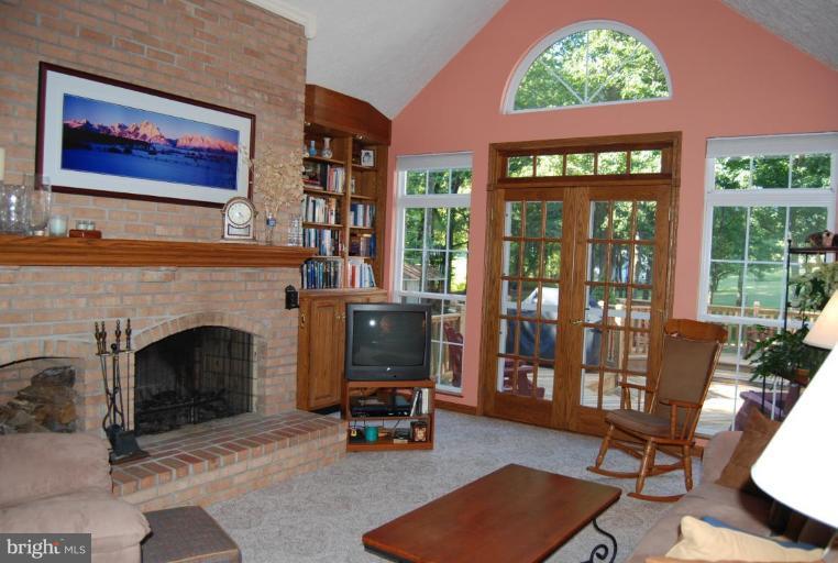 7218 Clyde Jones Road Owings, MD 20736 - Photo 6 of 9 a living room with furniture a fireplace and a floor to ceiling window