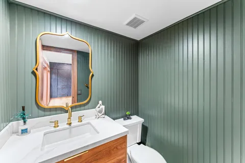 a bathroom with a toilet sink vanity and mirror
