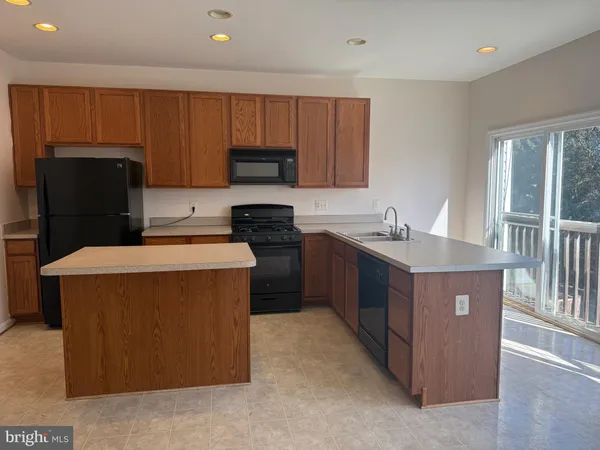 a kitchen with kitchen island granite countertop a stove top oven a refrigerator a sink and dishwasher