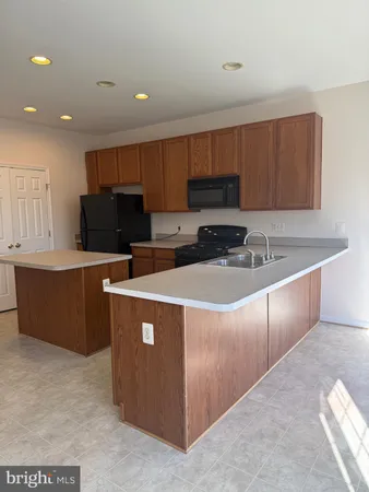 a kitchen with kitchen island cabinets a sink a counter and a refrigerator