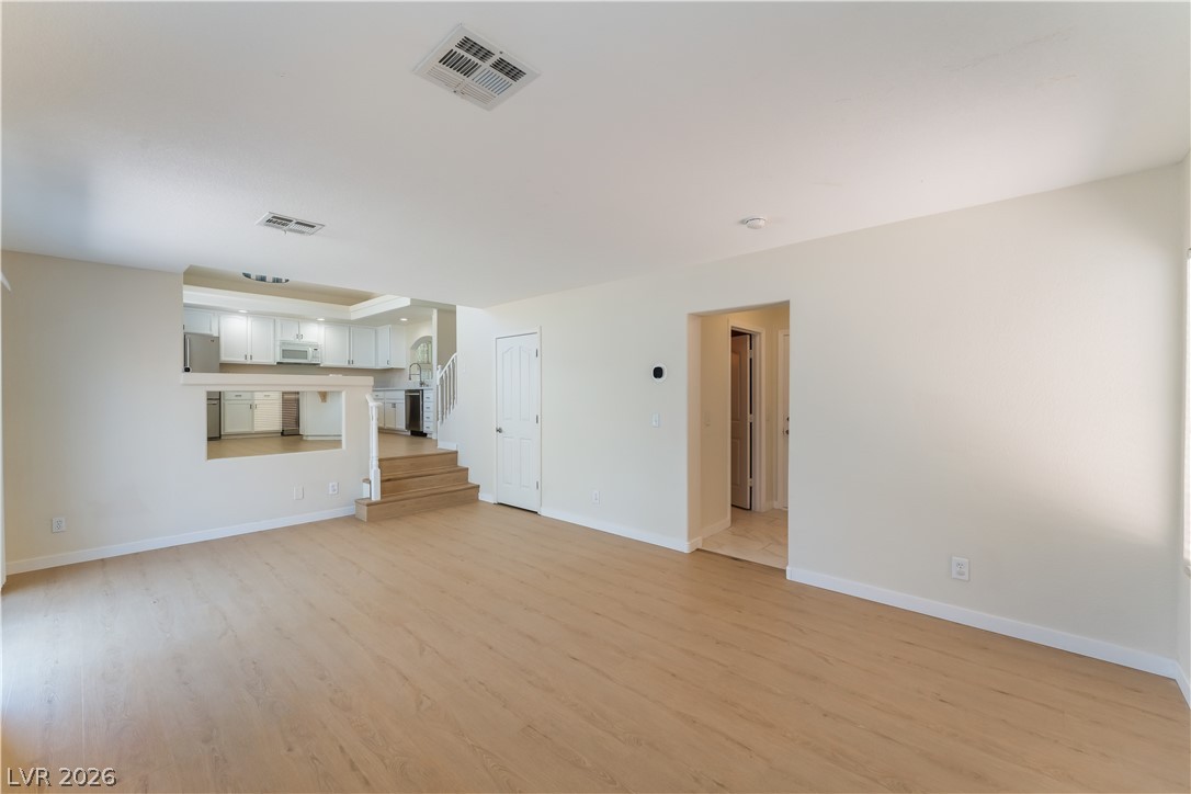 8872 Chapman Point Las Vegas, NV 89129 - Photo 10 of 29 Blonde hardwood floors flow into an inviting, open-concept living space with an elevated kitchen beyond.