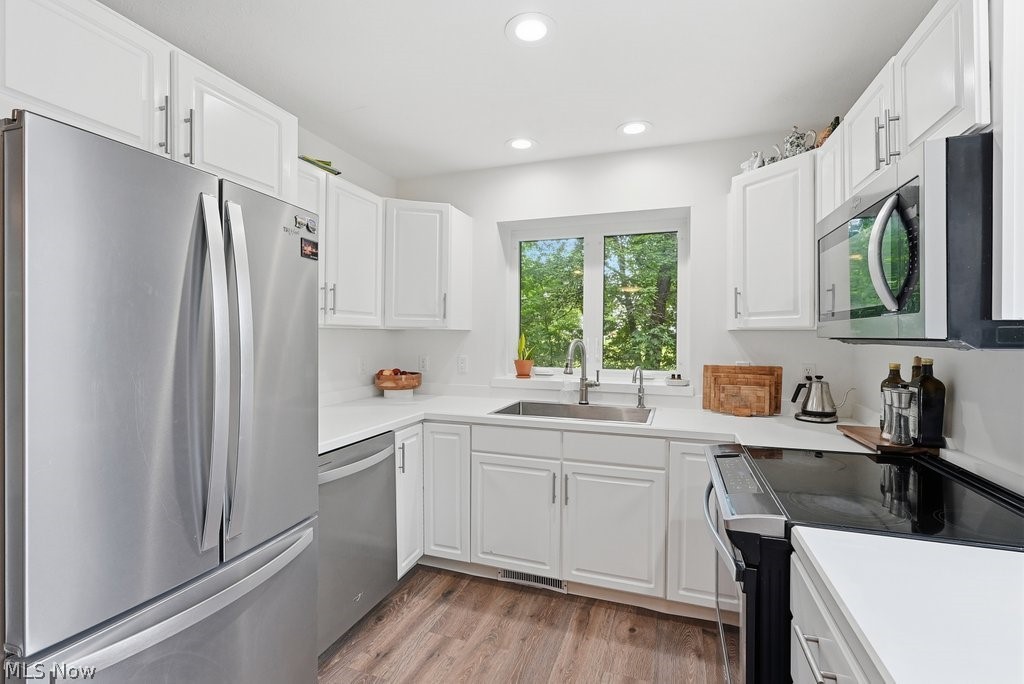 2323 Call Road Stow, OH 44224 - Photo 16 of 42 Kitchen featuring white shaker-style cabinetry, stainless steel appliances, wood-finish flooring, recessed lighting, and a window above the sink