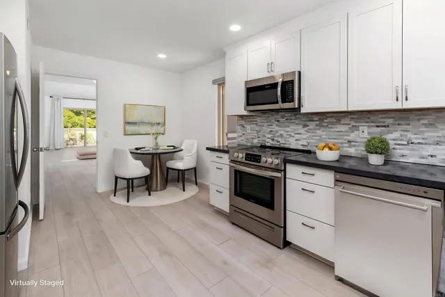 a kitchen with stainless steel appliances a stove a sink cabinets and a wooden floor